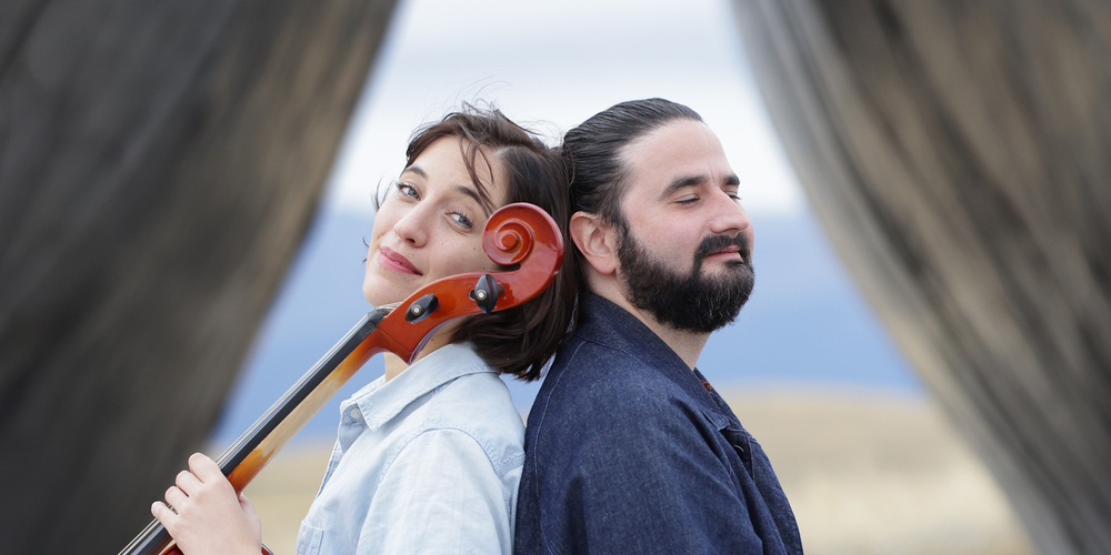 Camille Thomas, cello, and Julien Brocal, piano sit back-to-back in front of the Inverted Portal at Tippet Rise.
