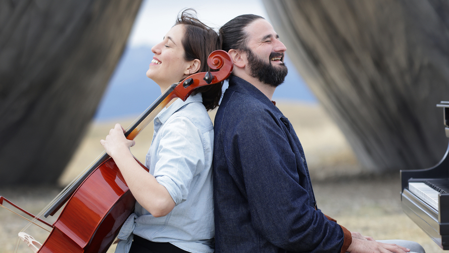 Camille Thomas, cello, and Julien Brocal, piano sit back-to-back in front of the Inverted Portal at Tippet Rise.