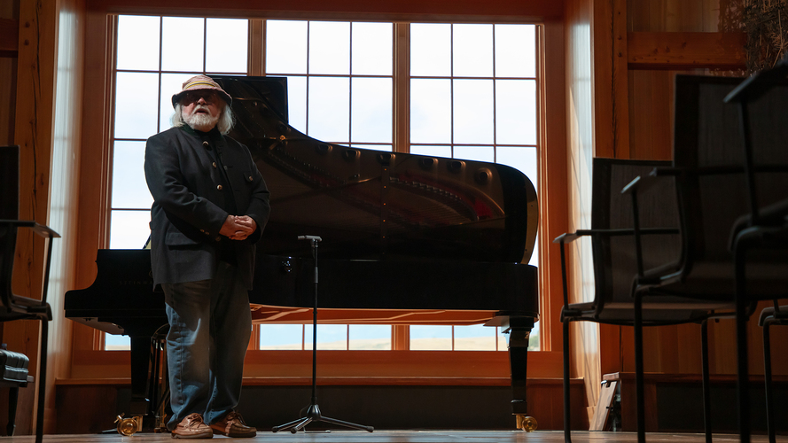 Peter Halstead stands in front of a Steinway piano in the Oliver Music Barn.