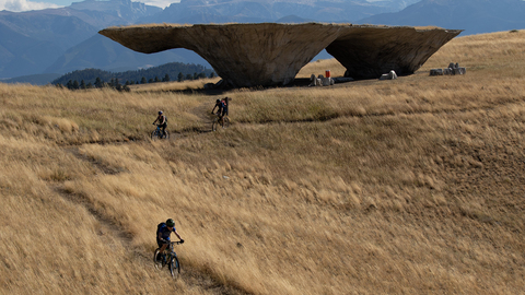 A group of cyclists bike down a trail from the Domo at Tippet Rise.