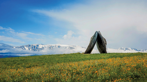 A monumental concrete sculpture called Inverted Portal stands in front of the Beartooth Mountains.