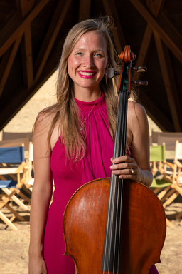 Arlen Hlusko is wearing a flowing pink dress while holding her cello.