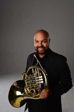 David Bryd-Marrow wears a black shirt and holds his french horn.