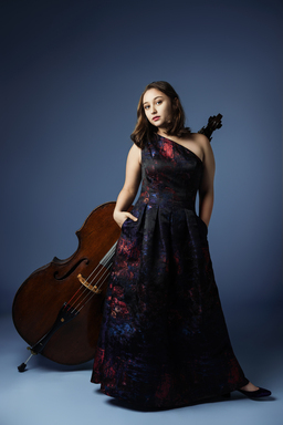 Nina Bernat wears a black, textured dress while posing with her double bass.