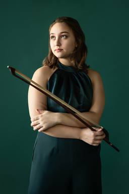 Nina Bernat wears a green jumper while holding the bow of her double bass.