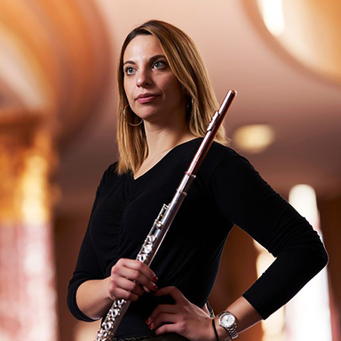 Jessica Sindell looks off into the sky holding her flute in one hand.