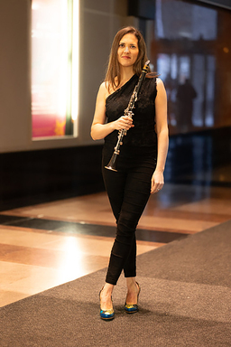 Yasmina Spiegelberg stands holding her clarinet.