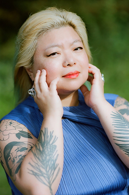 Yura Lee touches her cheeks in a blue blouse.