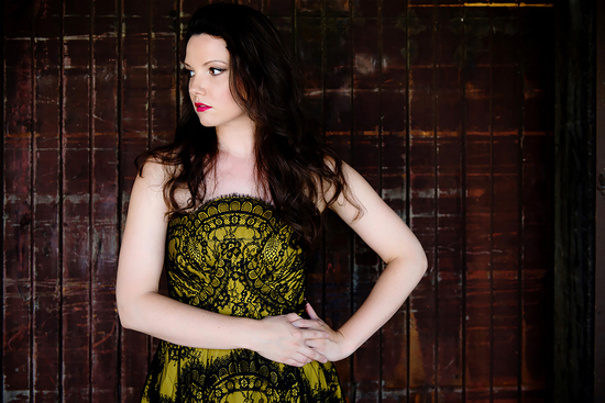 Mireille Asselin stands hand on hip in a yellow dress.