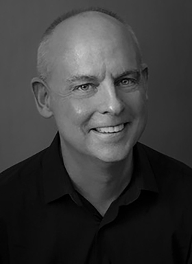 Richard Pearson Thomas smiles in a classic black & white portrait photo.